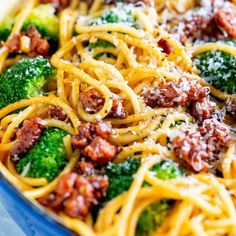 a pasta dish with broccoli, bacon and cheese on it in a blue bowl