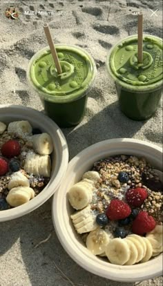 two cups filled with yogurt and fruit on the beach