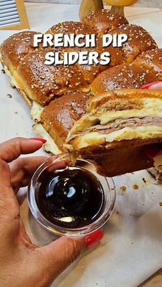 a person is holding a sandwich and dipping it into a small bowl with sauce on the side