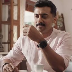 a man sitting at a table with a cup and saucer