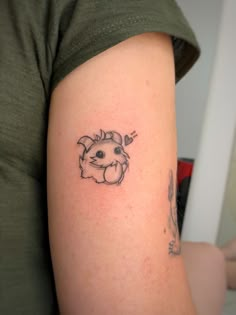 a woman's arm with a small tattoo of a cat on the back of her shoulder