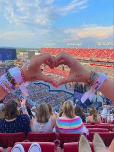 two hands making a heart with their fingers at a sporting event in front of an audience