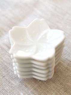 a stack of white dishes sitting on top of a cloth covered table next to each other