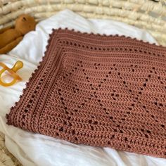 a crocheted blanket sitting on top of a bed next to a stuffed animal