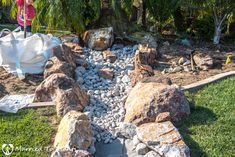 a woman standing in the middle of a garden area with rocks and gravel around it