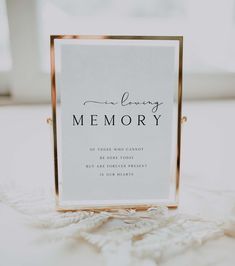 a memory sign sitting on top of a white tablecloth next to an open window