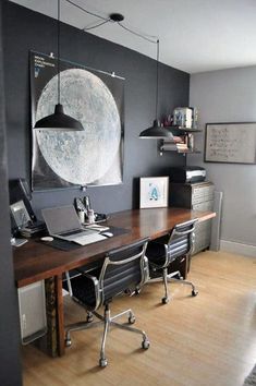 a desk with two chairs and a laptop on it in front of a large painting