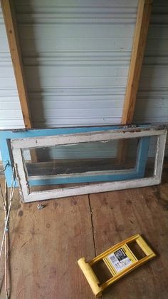 an old window sitting on the floor next to a yellow frame