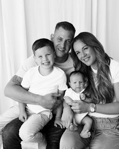 a man, woman and two children are sitting on a couch with their arms around each other