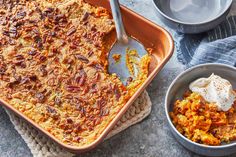 a casserole dish filled with carrots and topped with whipped cream next to other dishes