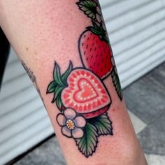 a strawberry and heart tattoo on the left leg, with flowers around it's edge