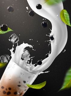 a glass filled with liquid and some green leaves flying around on a black background that appears to be falling into the water