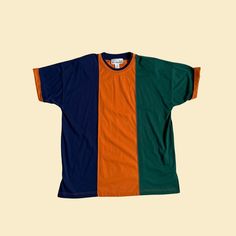 "Vintage 90s color block t-shirt, manufactured by Carolina Colours II. Originally a women's size 20W / 40, but could be worn by anyone today. Dark blue, dark green, and orange colorblock / vertical striped design. Features cuffed sleeves and shoulder pads.    - Brand: Carolina Colours II    - Size: Size 20W / 40    - Time Period: 1990s    - Color(s): Dark blue, dark green, orange    - Materials: Polyester, cotton    - Made in: Hong Kong    - Condition: In new old stock condition; still has a par 90s Colors, Color Block Tee, Time Period, Vertical Stripes, Green And Blue, Blue Dark, Vintage Colors, Green Orange, Stripes Design