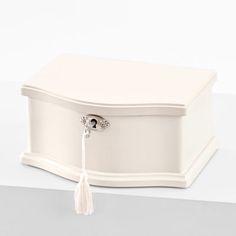 a white jewelry box with a tassel hanging from it