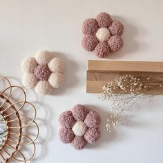 three pieces of decorative wall hangings on a white wall next to a vase with dried flowers