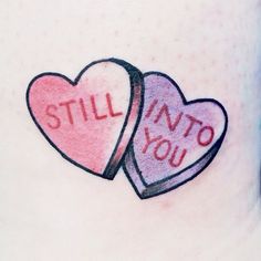 two hearts with the words still into you tattooed on their stomach, one is pink and the other is red