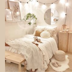 a bedroom with white bedding and lights on the wall, along with a wooden bench