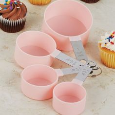 several cupcakes are being cut with scissors on a table next to other cupcakes