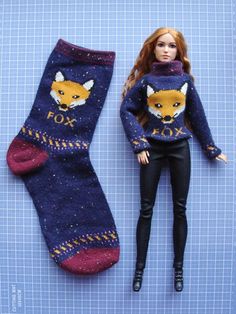 a barbie doll laying next to a sock with a fox on it's side