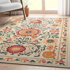 an area rug with flowers on it in front of a chair and window sill