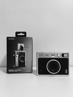 a black and white photo of an old camera next to a box with the same product on it