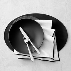 a black and white photo of a plate with silverware on it next to napkins