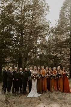 a group of people standing next to each other in front of some trees and grass