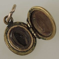 This is a gold plated locket from the late Victorian period The oval locket is decorated with light traces of engine turning and has a suspension loop. Inside there is a frame and glass holding a lock of hair. The locket measures 14mm x 10mm x 2mm - it is tiny and is in 80% mint condition - light wear and the majority of the engine turning has worn away. Open Locket, Victorian Locket Necklace With Antique Finish, Victorian Pendant Locket Necklace With Antique Finish, Victorian Antique Finish Pendant Locket Necklace, Antique Locket Pendant Necklace, Antique Pendant Locket Necklace, Victorian Locket Pendant Necklace For Keepsakes, Victorian Oval Locket Necklace Keepsake, Victorian Oval Locket Necklace For Keepsake