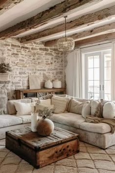 a living room filled with furniture and a fire place in front of a stone wall