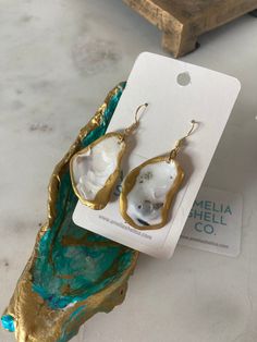 These earrings are 18k gold plated and hypoallergenic. They were hand made with a beautiful and carefully chosen pair of small oyster shells form the beaches of Amelia Island, and are hand painted with gold and clear acrylic. Gold Shell Dangle Earrings, Brass Shell Earrings For Gift, Unique Gold Shell Earrings, Unique Gold Earrings For Beach, Handmade Ocean-inspired Gold Earrings, Ocean-inspired Gold Jewelry With Ear Wire, Gold Pearl Drop Earrings With Ocean-inspired Style, Ocean-inspired Gold Pearl Earrings For Beach, Gold Dangle Shell Earrings Ocean-inspired