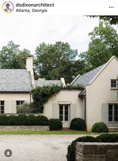 an image of a house that is in the middle of a driveway with bushes growing on it