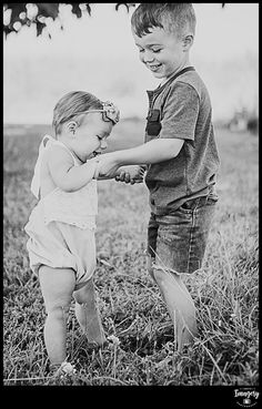 two young children playing with each other in the grass