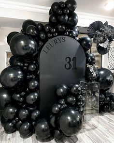 black balloons in the shape of an arch with a number on it and a plaque