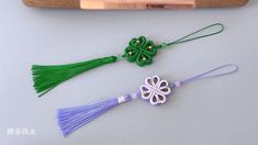 three tassels with green and purple beads are on a table next to a bat