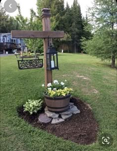 a wooden cross sitting on top of a lush green field next to a potted plant