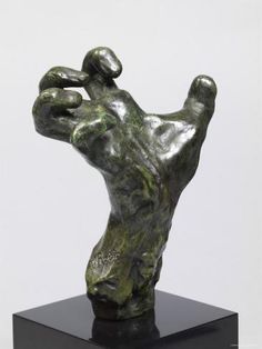 a bronze sculpture of a hand reaching for something