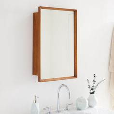 a bathroom sink with a mirror above it next to a towel rack and two vases