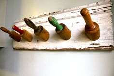 five wooden pegs are lined up in a row on a white painted board, with green and red pins sticking out of them