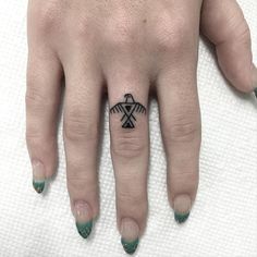 a woman's hand with a small black and white tattoo on the middle finger