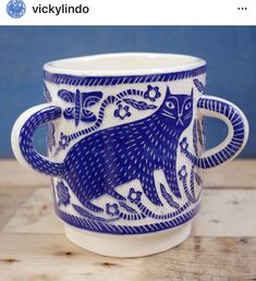 two blue and white cups sitting on top of a wooden table