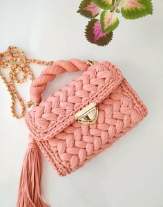 a pink purse sitting on top of a white table next to a green leafy plant