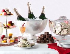 a table topped with lots of desserts and bottles of wine on top of it