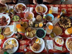 people are sitting at a table full of breakfast foods