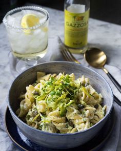 a bowl filled with pasta and veggies next to a drink