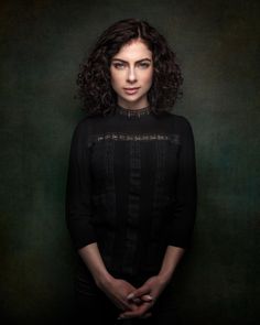 a woman with curly hair standing in front of a green background