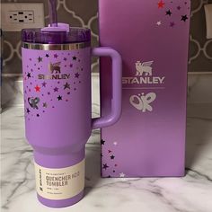 a purple starbucks cup next to a pink box on a marble counter with the lid open