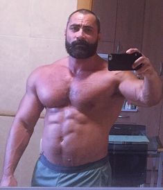 a shirtless man taking a selfie in front of a mirror with his cell phone