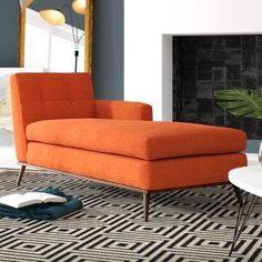 an orange chaise lounge chair sitting on top of a black and white area rug