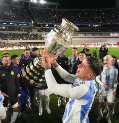 a man holding up a trophy while standing in front of other people on a field