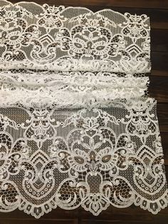 three pieces of white lace sitting on top of a wooden floor next to each other